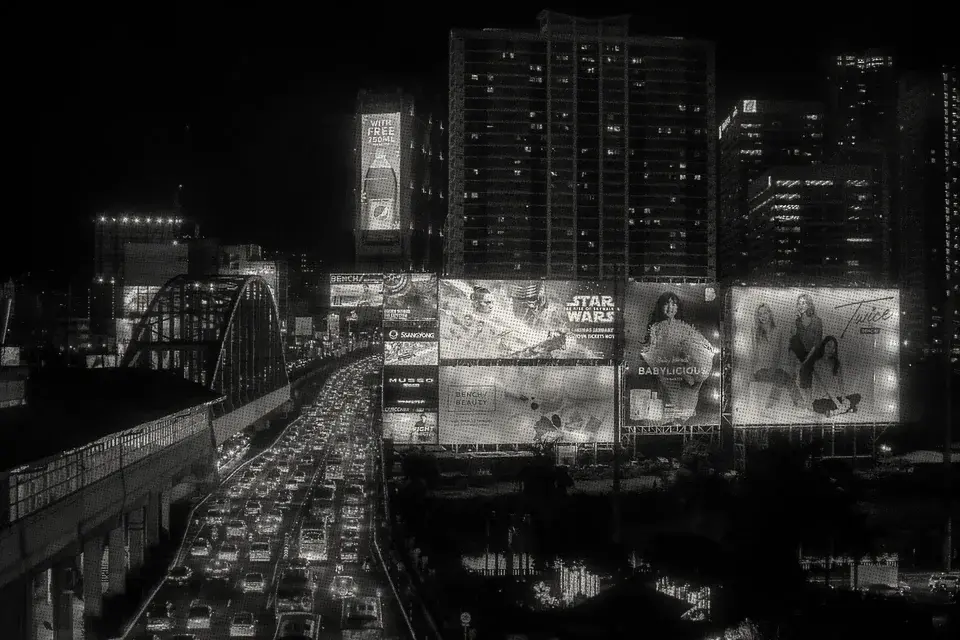 Illuminated billboards lining a busy Metro Manila highway at night